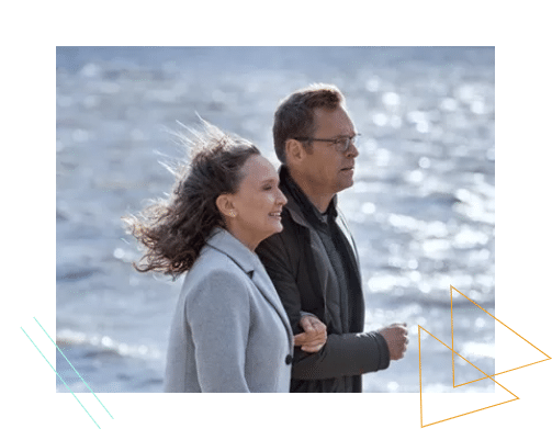 Mature couple walking on the beach waering Oticon Real hearing aids